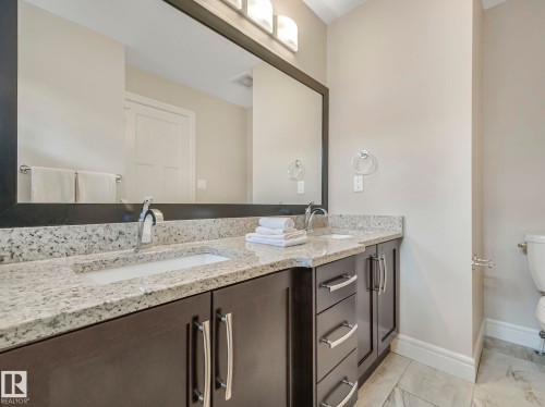 Bathroom featuring a double vanity with granite countertops, undermount sinks, and dark wood cabinetry with chrome hardware - 2 10319 120 Street, Edmonton, AB - Indoor Photo Showing Bathroom