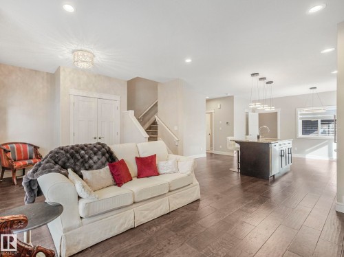This open-concept living area features rich hardwood flooring, recessed lighting, and a decorative ceiling light fixture - 2 10319 120 Street, Edmonton, AB - Indoor Photo Showing Living Room