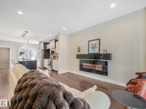 Living area featuring hardwood floors, a wall-mounted fireplace, and recessed lighting - 2 10319 120 Street, Edmonton, AB - Indoor Photo Showing Living Room With Fireplace
