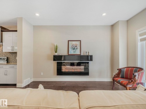 Living room featuring dark hardwood floors, recessed lighting, and a modern wall-mounted fireplace - 2 10319 120 Street, Edmonton, AB - Indoor