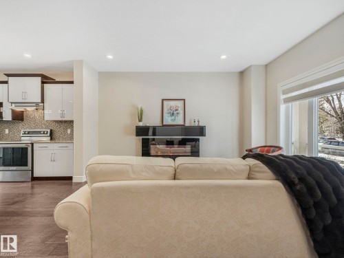 This living area features rich wood flooring and a contemporary fireplace - 2 10319 120 Street, Edmonton, AB - Indoor Photo Showing Living Room