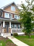 The property features a brown facade with white trim, a welcoming front porch with white railings and columns, and a concrete walkway leading to the entrance - 16464 15 Avenue, Edmonton, AB  - Outdoor With Deck Patio Veranda With Facade 