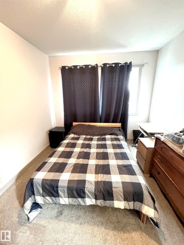 This room features carpeting, light-colored walls, and a window with dark curtains - 16464 15 Avenue, Edmonton, AB - Indoor Photo Showing Bedroom