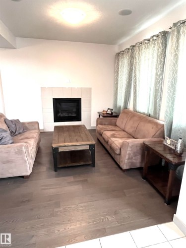 Living area featuring hardwood flooring, a fireplace with a tiled surround, and recessed lighting - 16464 15 Avenue, Edmonton, AB - Indoor Photo Showing Living Room With Fireplace