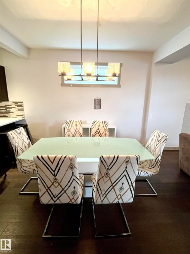 Dining area featuring dark flooring and a contemporary light fixture - 16464 15 Avenue, Edmonton, AB - Indoor