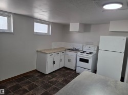 Kitchen with white cabinetry, white appliances, and light countertops - 