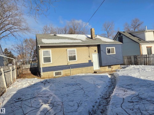Snow covered property featuring a fenced backyard, a chimney, a shingled roof, and a patio area - 13023 Sherbrooke Avenue, Edmonton, AB - Outdoor