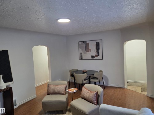 Living room featuring arched walkways, wood finished floors, and a textured ceiling - 13023 Sherbrooke Avenue, Edmonton, AB - Indoor