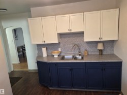 Kitchen featuring white cabinetry, arched walkways, blue cabinetry, and light countertops - 