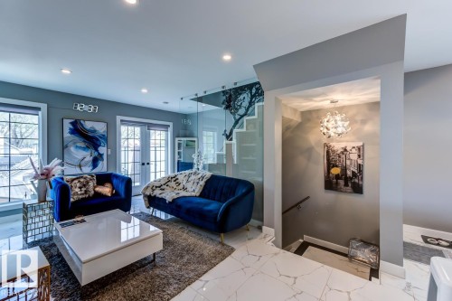 The living area features white marble flooring, recessed lighting, and a glass-paneled wall - 9526 109A Avenue, Edmonton, AB - Indoor