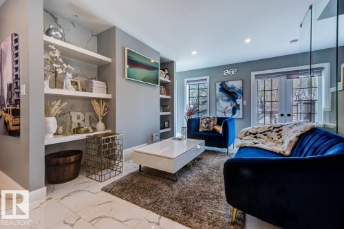 This living area features recessed lighting, elegant white floating shelves, and a gray textured accent wall - 9526 109A Avenue, Edmonton, AB - Indoor