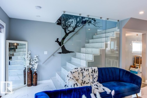 The property features a staircase with marble treads and glass railings, complemented by a wall-mounted tree silhouette design - 9526 109A Avenue, Edmonton, AB - Indoor Photo Showing Other Room