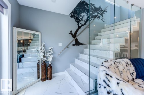 The property features a staircase with white marble-patterned treads, a glass railing, and a sleek metal handrail - 9526 109A Avenue, Edmonton, AB - Indoor