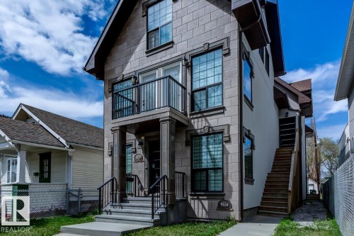 The property features a stone facade, a balcony with black railings, and an exterior staircase - 9526 109A Avenue, Edmonton, AB - Outdoor With Facade