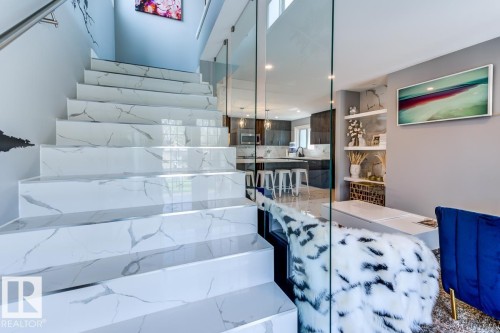 The property features a staircase with white marble-patterned steps and a glass railing - 9526 109A Avenue, Edmonton, AB - Indoor Photo Showing Other Room