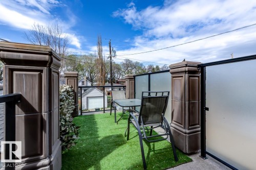 The property features an outdoor patio area with artificial turf, bordered by decorative pillars and frosted glass panels - 9526 109A Avenue, Edmonton, AB - Outdoor With Exterior