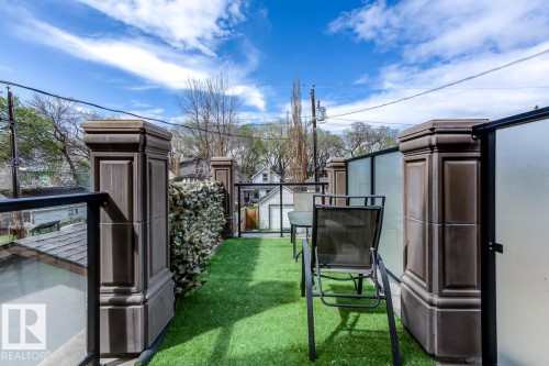 Rooftop patio featuring artificial turf, decorative pillars, and glass railings with frosted privacy panels - 9526 109A Avenue, Edmonton, AB - Outdoor