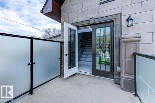 The property features a stone exterior with a decorative outdoor wall lantern and a glass-paneled door - 9526 109A Avenue, Edmonton, AB - Outdoor With Exterior