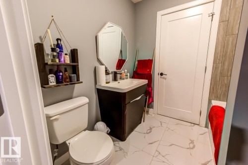 The bathroom features a toilet, a vanity with a sink, and an octagonal mirror - 9526 109A Avenue, Edmonton, AB - Indoor Photo Showing Bathroom