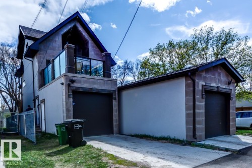 The property features a stone and stucco exterior, a second-story balcony with glass railings, and a garage door - 9526 109A Avenue, Edmonton, AB - Outdoor