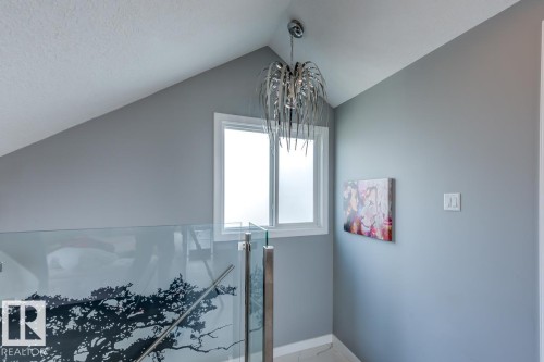 This interior space features an angled ceiling, a window with frosted glass, and a contemporary chandelier - 9526 109A Avenue, Edmonton, AB - Indoor Photo Showing Other Room