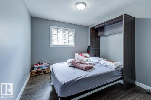 Bedroom featuring a white framed window with blinds, a ceiling-mounted light fixture, and wood-look flooring - 9526 109A Avenue, Edmonton, AB - Indoor Photo Showing Bedroom