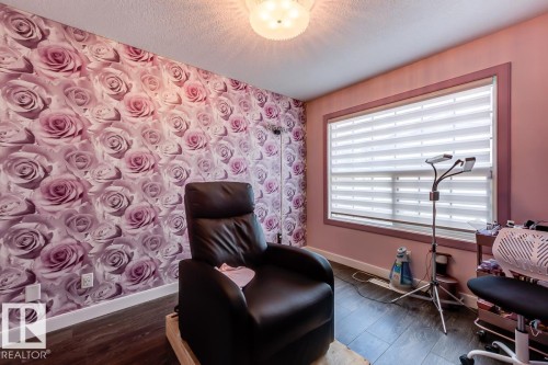 This room features a wall with rose-patterned wallpaper, a window with horizontal blinds, and dark wood-style flooring - 9526 109A Avenue, Edmonton, AB - Indoor Photo Showing Other Room
