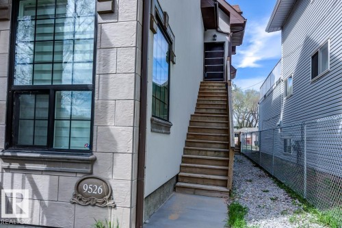 The property features an exterior with textured stone-like siding and large windows with dark frames - 9526 109A Avenue, Edmonton, AB - 