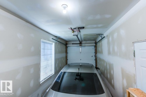 The garage features a window with blinds, an overhead garage door, and a ceiling-mounted light fixture - 9526 109A Avenue, Edmonton, AB - Indoor Photo Showing Garage