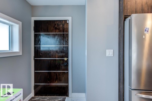 The property features a dark wood door with horizontal accents, a window with a white frame, and light gray walls - 9526 109A Avenue, Edmonton, AB - Indoor Photo Showing Other Room