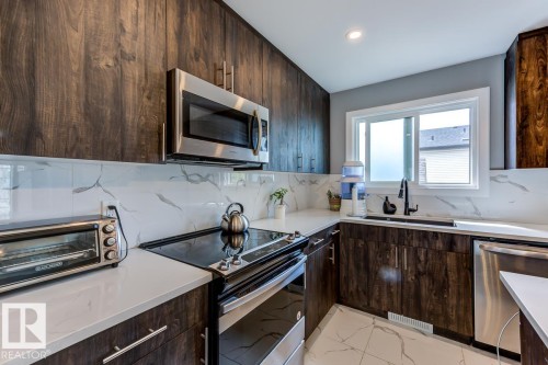 The kitchen features dark wood cabinetry, white countertops, and a white backsplash with gray veining - 9526 109A Avenue, Edmonton, AB - Indoor Photo Showing Kitchen
