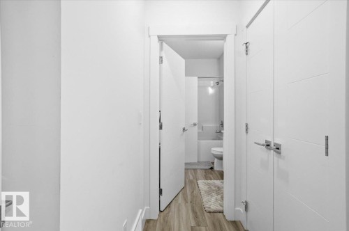 Hallway with light-toned flooring, white walls, and modern white doors with horizontal paneling and chrome hardware - 16624 32 Avenue, Edmonton, AB - Indoor Photo Showing Other Room