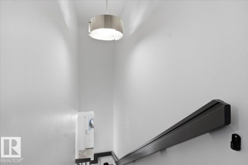 Stairwell with a modern ceiling light fixture and dark-toned handrail - 16624 32 Avenue, Edmonton, AB - Indoor Photo Showing Other Room