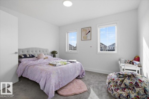 This bright room features two windows providing natural light, a light gray carpet, and white painted walls - 16624 32 Avenue, Edmonton, AB - Indoor Photo Showing Bedroom