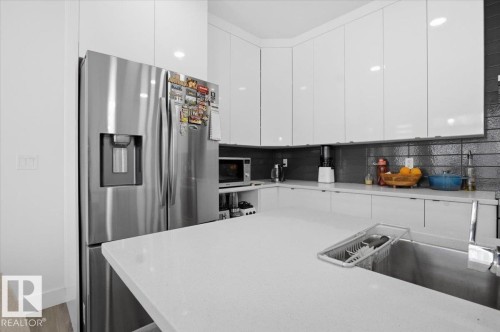 The kitchen features white cabinetry, a stainless steel refrigerator with a dispenser, and light-colored countertops - 16624 32 Avenue, Edmonton, AB - Indoor Photo Showing Kitchen With Stainless Steel Kitchen With Upgraded Kitchen