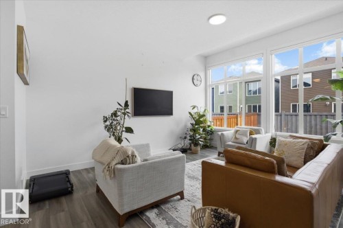 Spacious living area featuring large windows providing natural light, light-toned walls, and wood-style flooring - 16624 32 Avenue, Edmonton, AB - Indoor Photo Showing Living Room