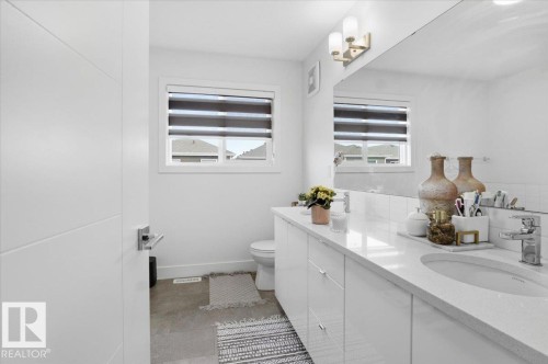 Bathroom vanity with dual sinks, a large mirror, and overhead lighting - 16624 32 Avenue, Edmonton, AB - Indoor Photo Showing Bathroom