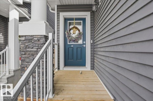 The property features a front entrance with a blue door, a wooden ramp, and stone accents on the porch column - 16624 32 Avenue, Edmonton, AB - Outdoor With Exterior