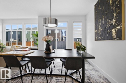 The dining area features a contemporary chandelier, large windows with blinds, and a sliding glass door - 16624 32 Avenue, Edmonton, AB - Indoor Photo Showing Dining Room