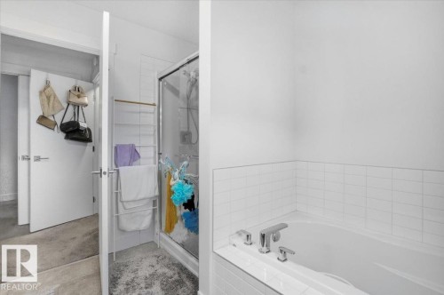 Bathroom featuring a white bathtub with chrome fixtures, a subway tile surround, and a glass-enclosed shower - 16624 32 Avenue, Edmonton, AB - Indoor Photo Showing Bathroom