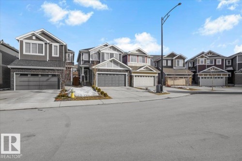 The property is a two-story home featuring a two-car garage, a paved driveway, and a front exterior with a combination of siding and stone detailing - 16624 32 Avenue, Edmonton, AB - Outdoor With Facade