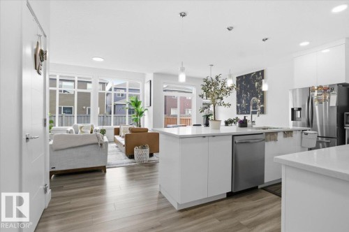 The property features an open-concept living area with light-toned flooring and large windows - 16624 32 Avenue, Edmonton, AB - Indoor Photo Showing Kitchen With Upgraded Kitchen