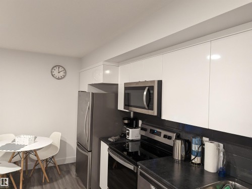 The kitchen features a stainless steel refrigerator, microwave, and electric range - 16624 32 Avenue, Edmonton, AB - Indoor