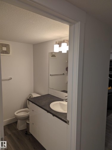 Bathroom featuring a vanity with a white rectangular sink, dark countertop, and white cabinetry - 16624 32 Avenue, Edmonton, AB - Indoor Photo Showing Bathroom