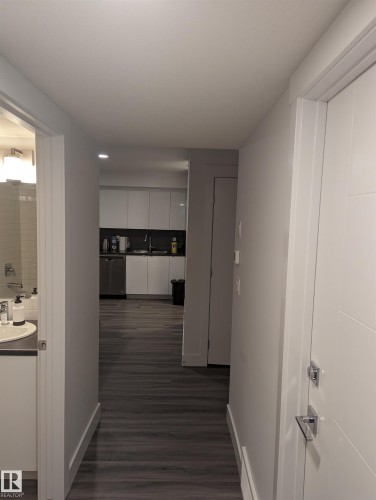 The property features dark wood-style flooring throughout, with a kitchen visible in the background, complete with white cabinetry and stainless steel appliances - 16624 32 Avenue, Edmonton, AB - Indoor Photo Showing Other Room
