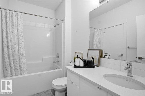 The bathroom features a clean white vanity with a single sink, a large mirror, and a combination bathtub and shower with white subway tile - 16624 32 Avenue, Edmonton, AB - Indoor Photo Showing Bathroom