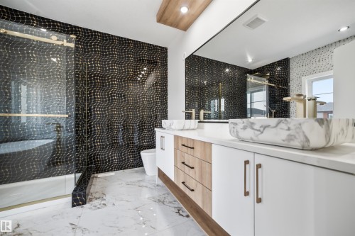 This bathroom features a double vanity with two vessel sinks, a large mirror, and a spacious shower with a glass enclosure - 423 Robinson Boulevard, Leduc, AB - Indoor Photo Showing Bathroom