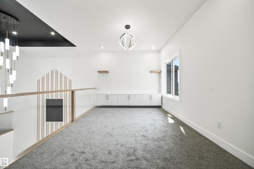 The property features a bright and spacious interior with white walls, recessed lighting, and a contemporary chandelier - 423 Robinson Boulevard, Leduc, AB - Indoor Photo Showing Other Room
