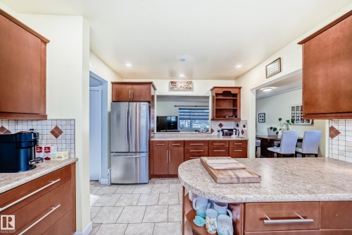 The kitchen features wood cabinetry, a stainless steel refrigerator, and light-colored countertops - 4446 116 Avenue, Edmonton, AB 