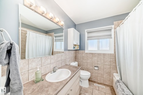 Bathroom featuring a vanity with a sink, a mirror with overhead lighting, a window, and tiled flooring - 4446 116 Avenue, Edmonton, AB 